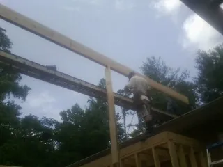 Carpenter setting a ridge beam over a new addition frame — Ice Dam Removal by Roofing Brothers in Rhodesdale