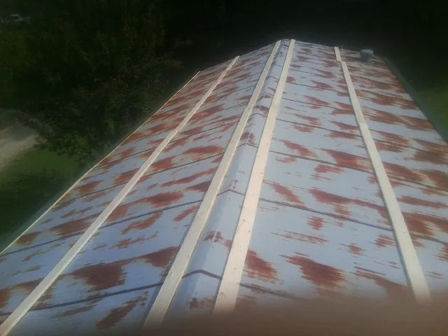 Rusted metal roof panels with new wood purlins before replacement — Storm Damage Roof Repair in Rhodesdale by Roofing Brothers
