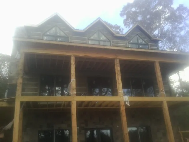 Dormers and porch framing on a large log home under construction — Roof Coating work by our crew in Rhodesdale