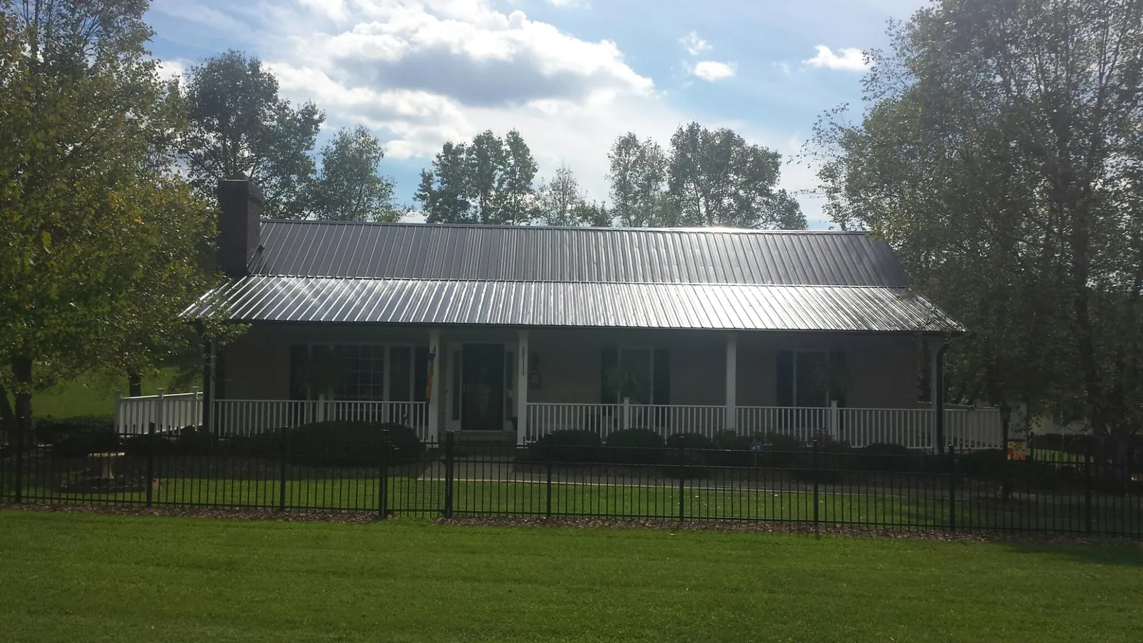 Gray metal roof on a brick ranch with a full width front porch — Gutter Guard Installation work by our crew in Rhodesdale
