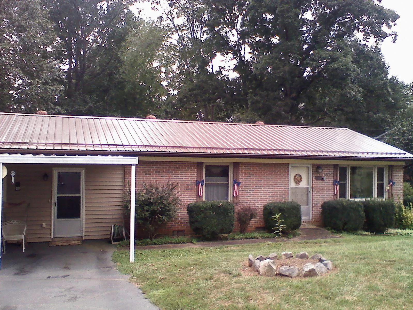 Bronze metal roof and carport on a brick ranch home — Roof Repair work by our crew in Rhodesdale