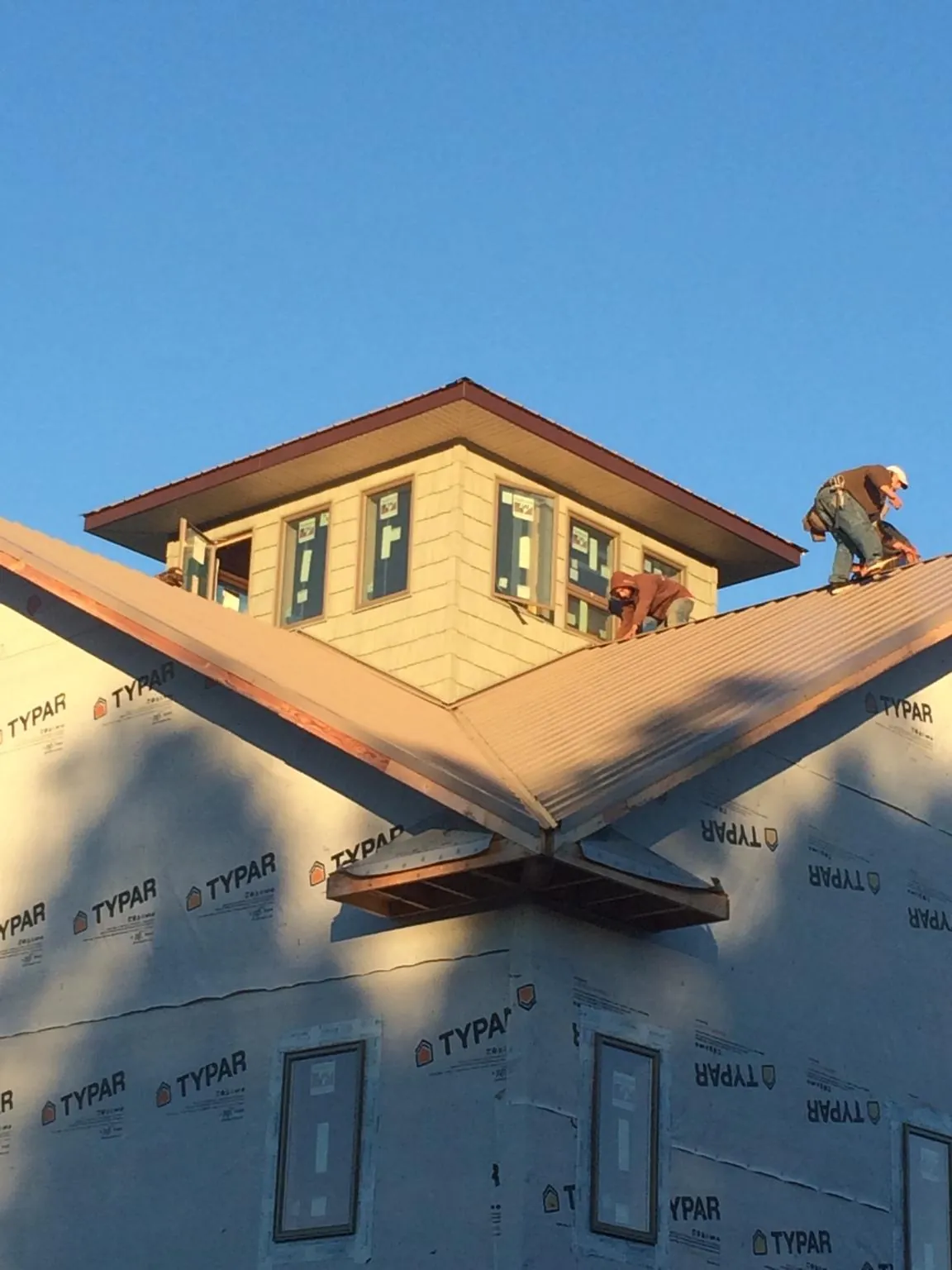 Roofers working around a rooftop cupola on a new metal roof at sunset — Roof Waterproofing in Rhodesdale by Roofing Brothers